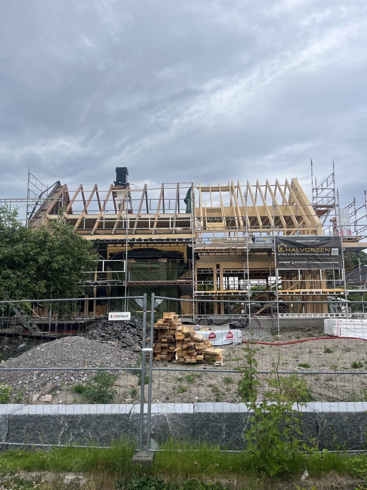 Pågående totalrenovering av sveitserhus i Vestfold – nytt reisverk og takkonstruksjon under arbeid, med stillas og Halvorsen-banner.
